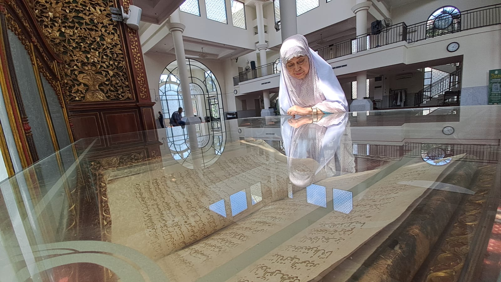 16258E22-C6F7-41B0-92F7-89D8928E19D9 Salah seorang pengurus Masjid Raya Fatimah melihat Al Qur’an raksasa di dalam etalse kaca, Rabu (29/3/2023) | MettaNEWS / Adinda Wardani